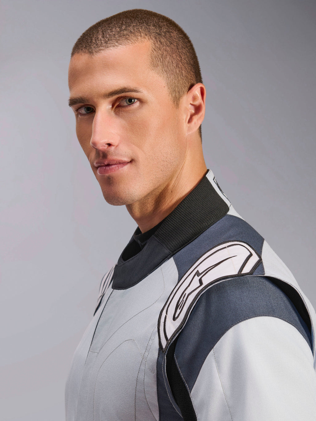 Alpinestars GP Pro Comp V2 FIA, macacão de automobilismo para homem, cinzento e preto, gola alta e logótipo branco no ombro.