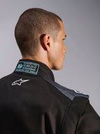 Macacão Alpinestars KMX-5 V3 em Preto e Dark Shadow, vista detalhada das costas e da gola com o logótipo Astars branco, etiqueta de certificação FIA 8877-2022 Grau 1 e painéis de malha ventilada nos ombros.