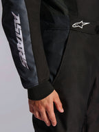 Macacão Alpinestars KMX-5 V3, macacão de karting, preto e Dark Shadow, pormenor em grande plano da anca e do braço, marca ASTARS branca na manga, logótipo branco na cintura, painéis de malha para ventilação e punho de malha