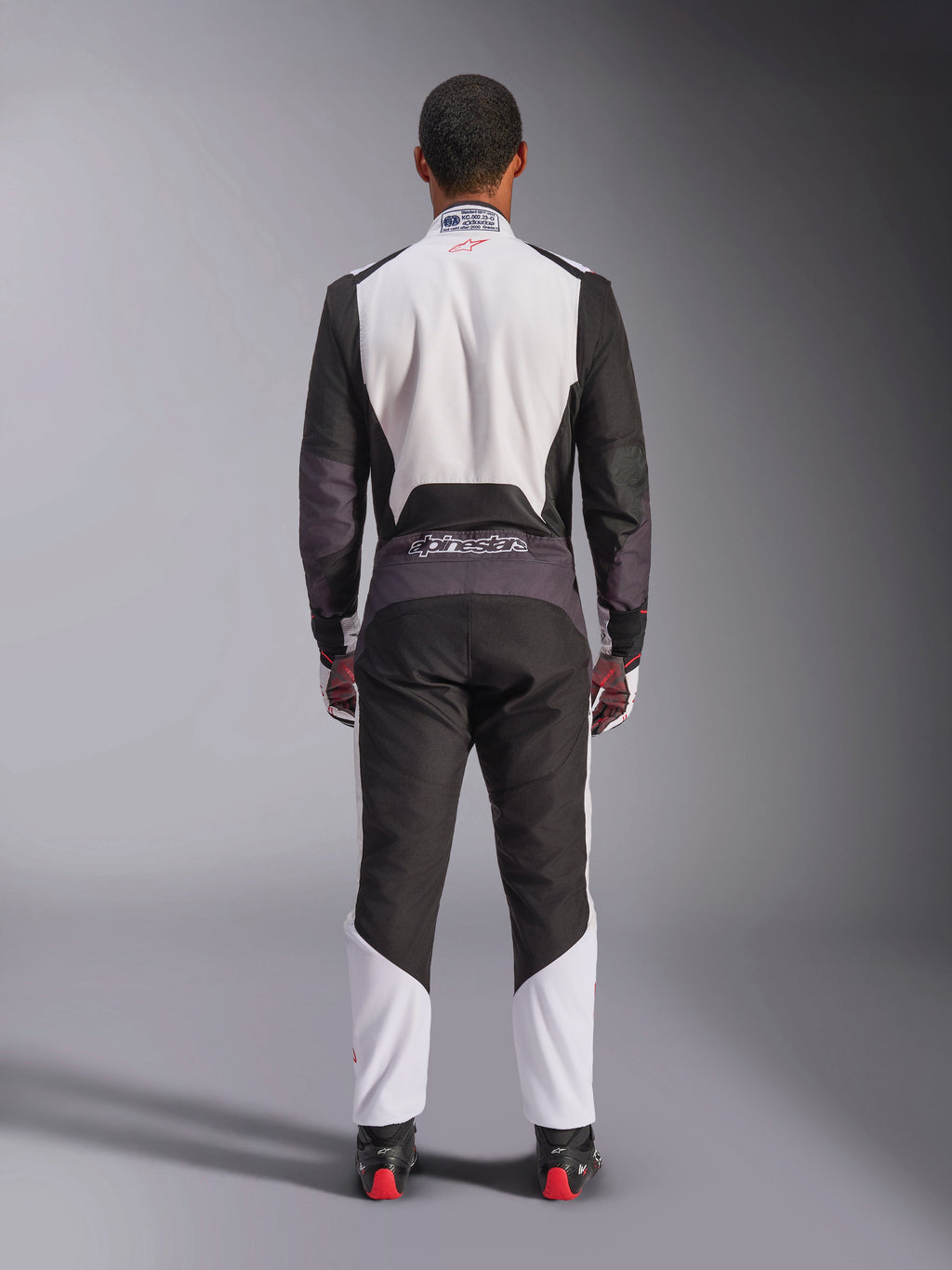 Macacão Alpinestars KMX-5 V3, fato de karting, branco, preto e vermelho vivo, vista traseira, macacão de corrida de uma peça com painéis de malha respirável e logótipo Alpinestars na cintura, usado com luvas e botas de corrida a combinar