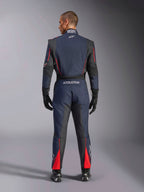 Vista traseira do Macacão Alpinestars GP Tech V4 em Azul Marinho, Preto e Vermelho, macacão de automobilismo de uma peça com painéis elásticos pretos e detalhes vermelhos, com o logótipo Alpinestars e detalhes de certificação FIA, usado com luvas e botas de corrida profissionais