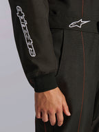 Pormenor do Fato Alpinestars KMX-9 V3 em Preto e Vermelho Fluo, com logótipo Alpinestars bordado a branco na manga, punho de malha e cinto na cintura com o logótipo Astars e costuras contrastantes em vermelho.
