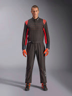Fato de Karting Alpinestars KMX-9 V3, preto e vermelho fluo, fato de corrida de peça única usado com luvas e botas coordenadas, com pormenores vibrantes nos ombros e costuras a vermelho, logótipo Alpinestars na parte inferior das pernas, design elegante de desporto motorizado para corridas em pista
