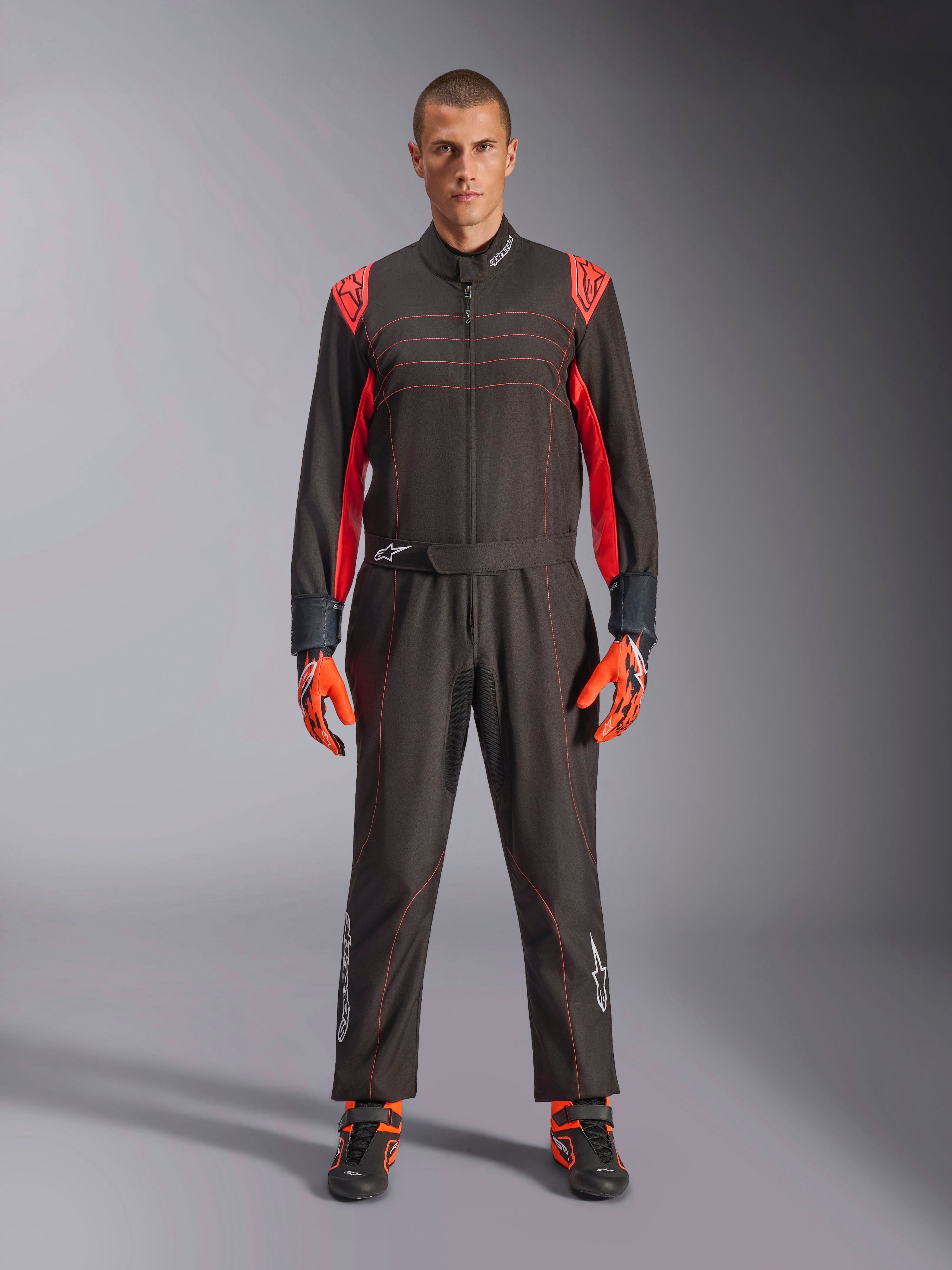 Fato de Karting Alpinestars KMX-9 V3, preto e vermelho fluo, fato de corrida de peça única usado com luvas e botas coordenadas, com pormenores vibrantes nos ombros e costuras a vermelho, logótipo Alpinestars na parte inferior das pernas, design elegante de desporto motorizado para corridas em pista