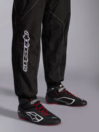 Alpinestars KMX-9 V3 Suit, Karting Suit, Black and White, lower leg view showing large white Alpinestars branding, worn with black and red racing boots, professional motorsport gear for karting