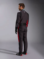 Fato Alpinestars KMX-9 V3 Graphic 3, preto e vermelho, vista traseira de modelo a usar equipamento completo de karting incluindo luvas pretas e botas de corrida, com painéis laterais vermelhos e detalhes do logótipo em branco