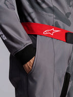 Macacão Alpinestars KMX-9 V3 Graphic 5, macacão de karting, cinzento escuro e preto com cinto vermelho, pormenor do cinto de cintura ajustável vermelho com logótipo branco, mão no bolso da coxa e punho de malha preta sobre tecido com padrão gráfico cinzento