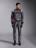 Macacão Alpinestars KMX-9 V3 Graphic 5, fato de karting, cinzento escuro e preto com grafismos estilo camuflagem, com uma faixa preta no peito com logótipo branco e um detalhe de cinto vermelho na cintura, usado com luvas e sapatos de corrida a condizer, equipamento profissional de desportos motorizados