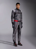 Fato Alpinestars KMX-9 V3 Graphic 5, fato de karting, cinzento escuro e preto com padrão gráfico camuflado, cinto vermelho com logótipo branco, usado com luvas e botas de corrida, equipamento profissional de desporto motorizado para karting