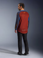 Alpinestars Maxdura Dual Jersey, Rust Brown e Mood Indigo, camisola de aventura para motociclismo vista de trás, painel de malha cor de ferrugem para ventilação, mangas azul-marinho com logótipos cor de laranja, usada com calças e botas de condução pretas, equipamento técnico para todo-o-terreno.