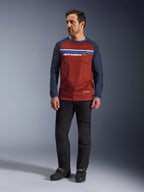 Alpinestars Maxdura Dual Jersey, Rust Brown e Mood Indigo, camisola de motociclismo de aventura com tronco em malha e mangas azul-marinho, usada por um modelo com calças de condução pretas e botas pretas, vestuário técnico dual-sport para condução off-road