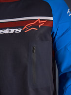 Alpinestars Maxdura Dual Jersey, close-up of chest and sleeve, Deep Gray and Royal Blue, featuring a zippered chest pocket, breathable mesh torso, and integrated padding on the sleeves, branded with the Alpinestars logo over red and white stripes.