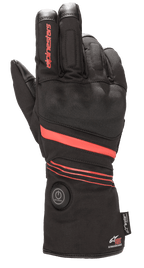 Luvas Alpinestars HT-5 Heat Tech Drystar®, luvas de motociclismo aquecidas, pretas com detalhes vermelhos, com um botão de ligar circular no punho, riscas vermelhas na mão e no pulso, logótipo Alpinestars no dedo, concebidas para proteção impermeável em climas frios.