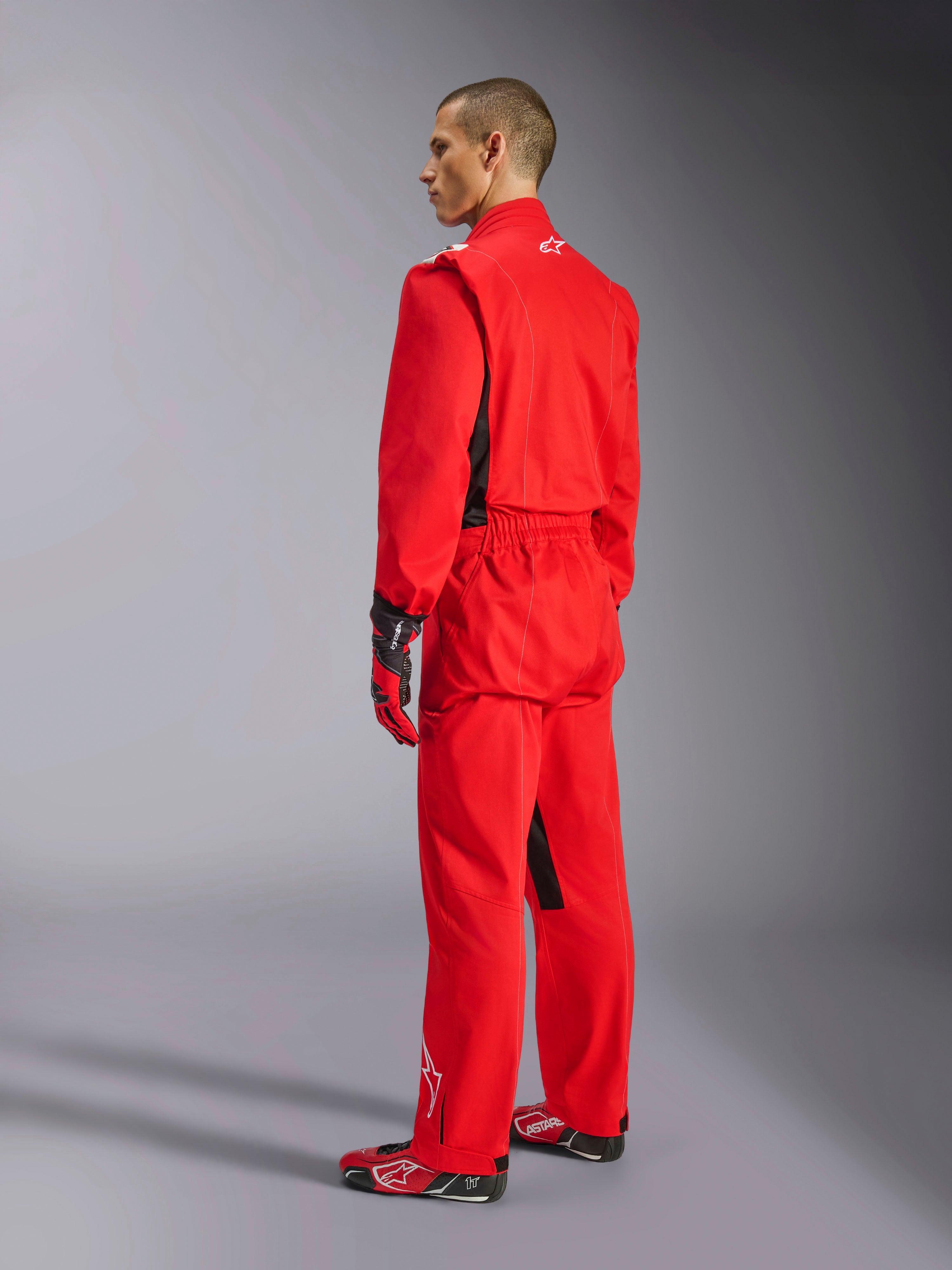 Fato Alpinestars Kart Indoor V2, fato de karting vermelho, vista traseira de três quartos num modelo, usado com luvas vermelhas e botas de competição a condizer, construção de sarja de camada única em poli-algodão, equipamento profissional para karting indoor