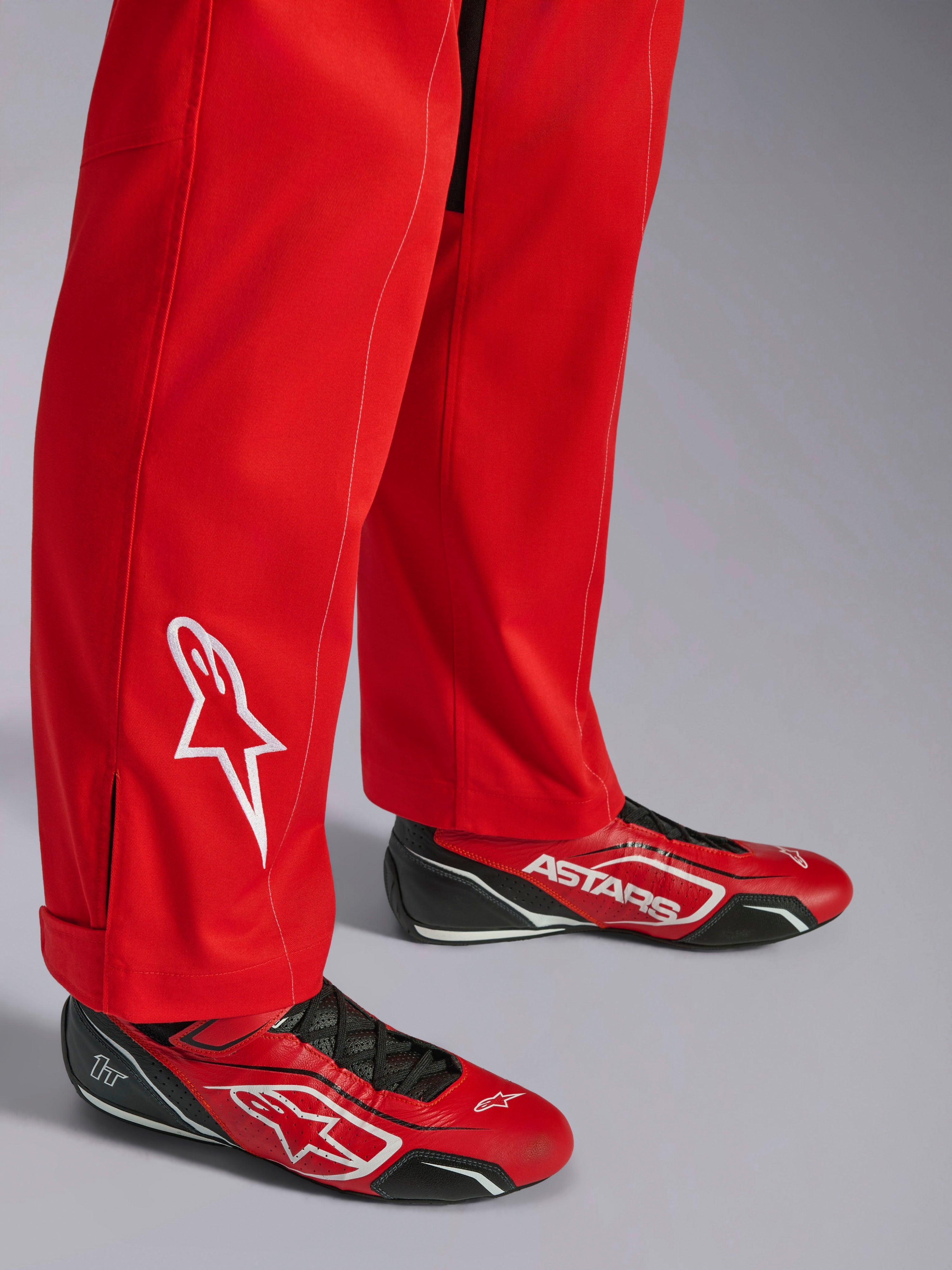 Fato Alpinestars Kart Indoor V2, vermelho, detalhe da parte inferior da perna com logótipo de estrela bordado a branco, usado com sapatos de karting vermelhos e pretos a condizer, material de sarja de poli-algodão de camada única para karting recreativo