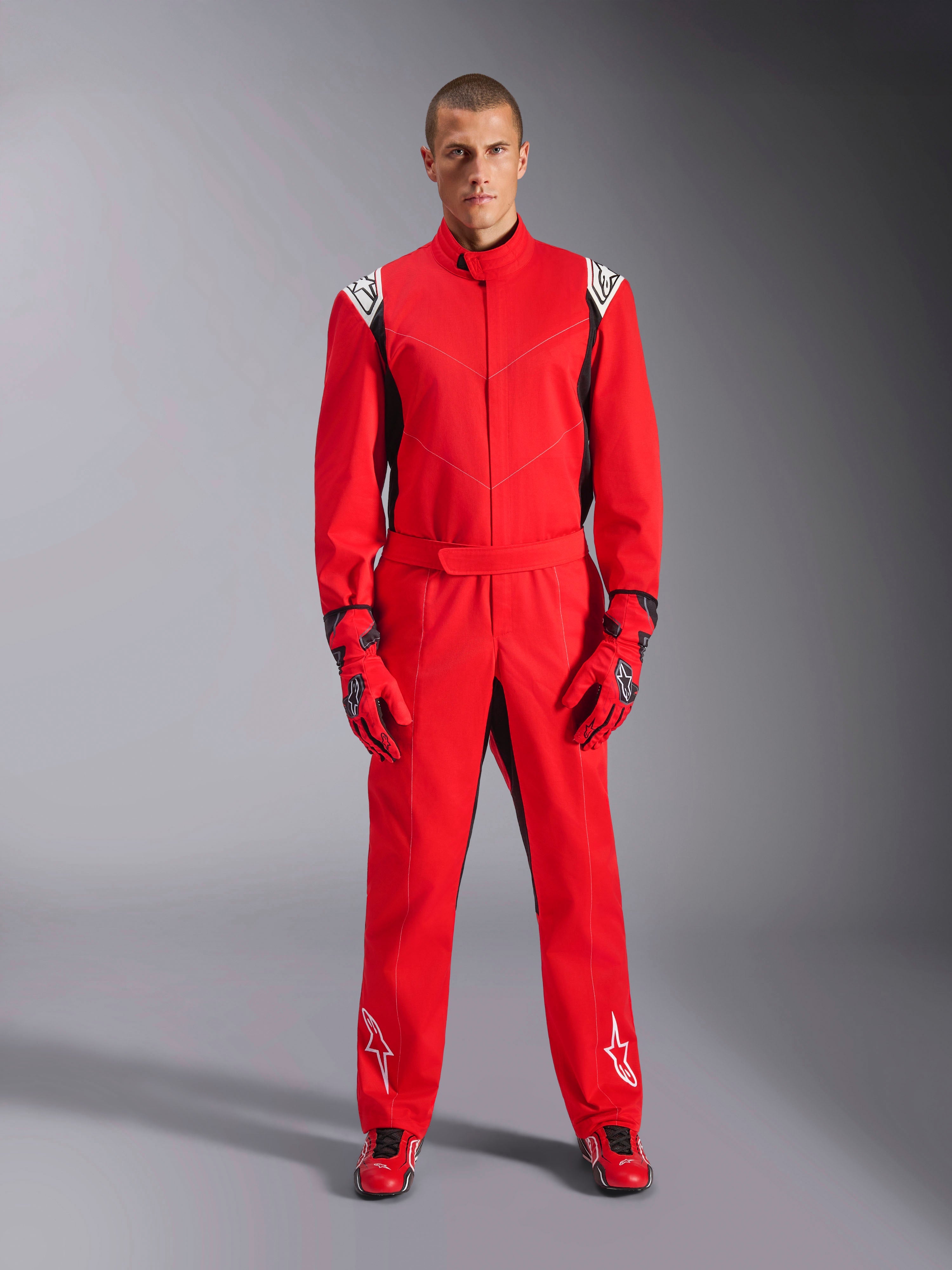 Alpinestars Kart Indoor V2 Suit, vermelho, fato de karting de peça única usado com luvas vermelhas e sapatos de corrida a condizer, com logótipos brancos nos ombros e pernas, detalhes pretos e um design aerodinâmico para corridas recreativas