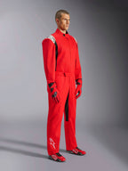 Fato Alpinestars Kart Indoor V2, macacão de karting vermelho, usado por um modelo com luvas e sapatos vermelhos e pretos a condizer, com logótipos brancos nos ombros e na parte inferior da perna, detalhes pretos, concebido para karting recreativo e pistas indoor