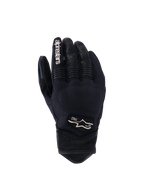 Luvas Alpinestars Tracker, luvas de motociclismo pretas, vista do dorso mostrando a construção em tecido elástico, detalhes em pele perfurada nos dedos e punho, marca branca no dedo indicador, logótipo Alpinestars com 1963 no dorso, zona dos nós dos dedos acolchoada, design urbano de punho curto