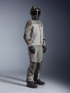 Alpinestars Nazca 3L GORE-TEX PRO Jacket, Adventure Motorcycle Jacket, Dark Gray and Mid Gray, worn as a complete outfit with matching adventure pants, featuring orange accents and Superfabric reinforcements, includes black adventure helmet and gloves, technical apparel for touring and off-road riding