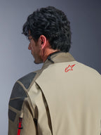 Casaco Alpinestars Nazca 3L GORE-TEX PRO, casaco de aventura em castanho Walnut Rock Brown, grande plano das costas e do ombro, logótipo de estrela vermelha na gola, painéis de reforço texturizados cinzentos, construção têxtil durável para motociclismo