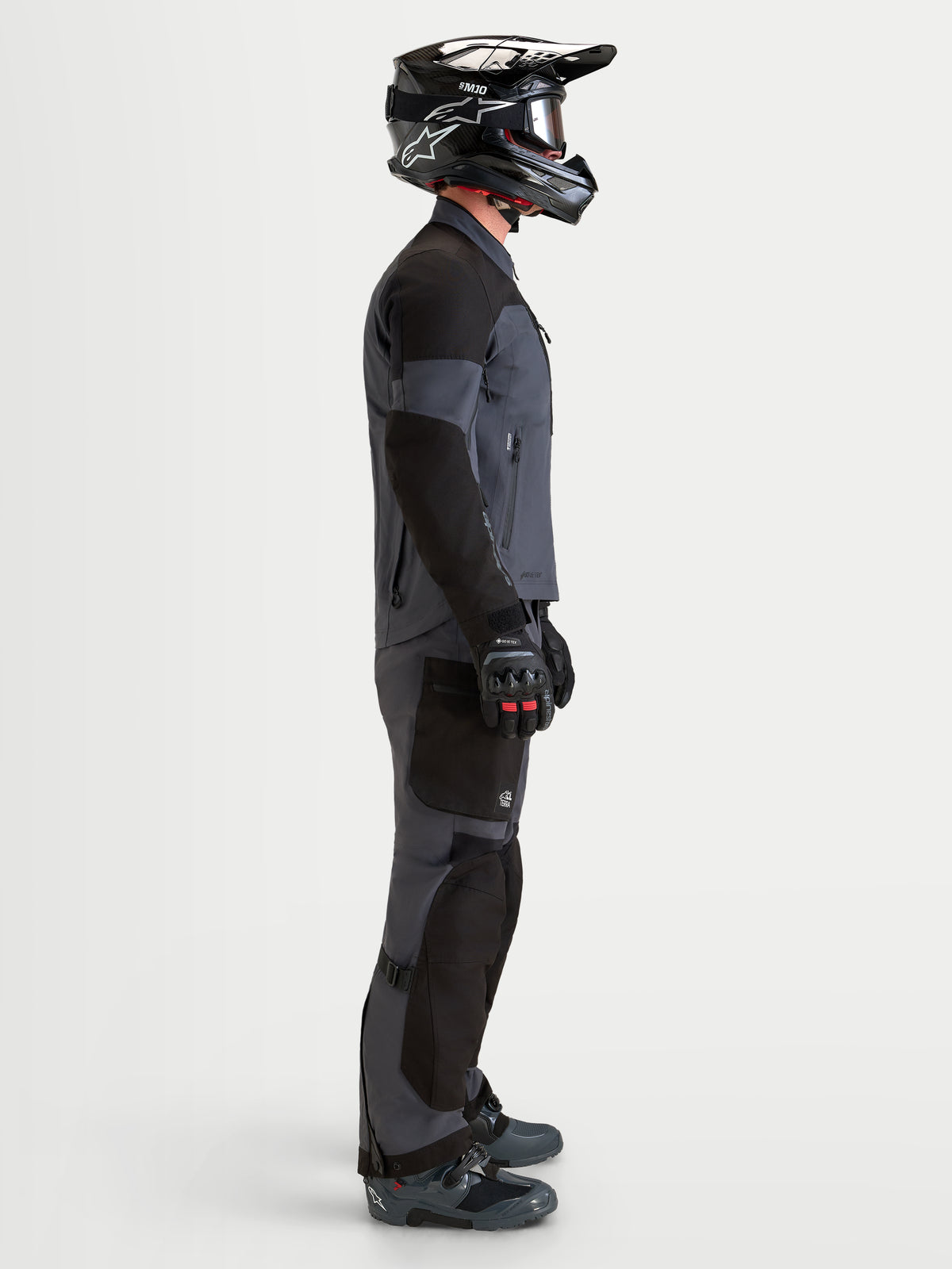 Alpinestars Arenis Gore-Tex Gear Set, equipamento de moto adventure para homem, preto e cinzento-escuro, vista de perfil lateral num modelo a usar capacete e botas a combinar, vestuário impermeável para todo-o-terreno