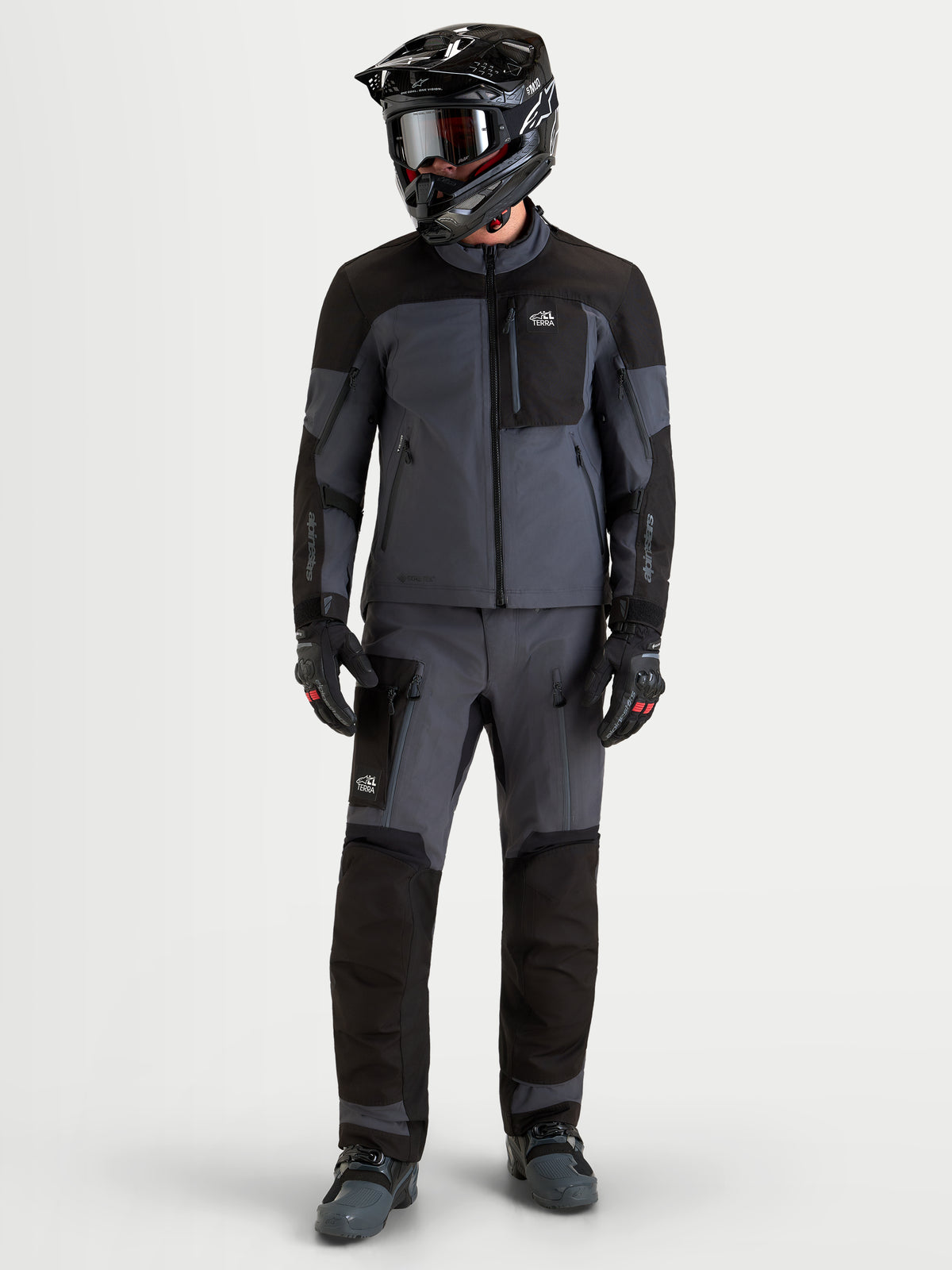 Alpinestars Arenis Gore-Tex Gear Set, casaco e calças de moto adventure para homem em preto e cinzento escuro, vista frontal completa num modelo com equipamento e capacete a condizer, vestuário de condução todo-o-terreno impermeável
