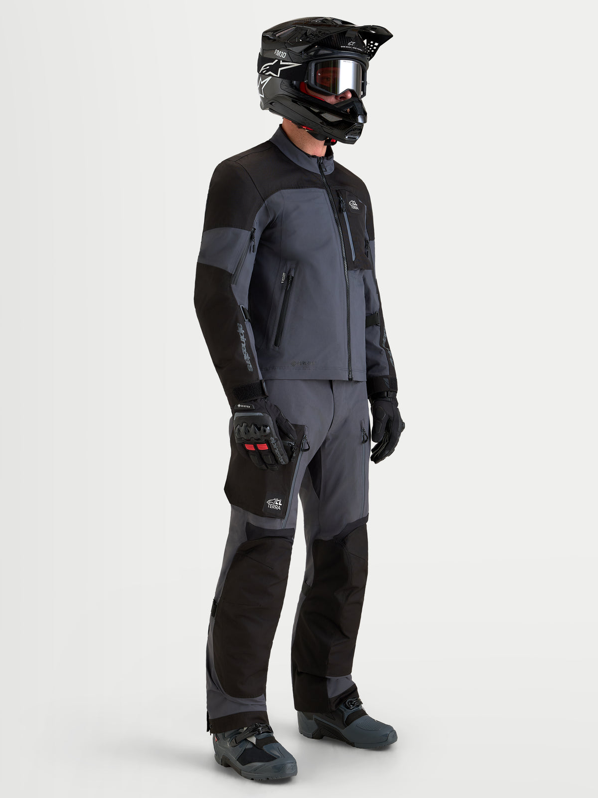 Alpinestars Arenis Gore-Tex Gear Set, equipamento de moto adventure para homem, preto e cinzento profundo, vista de perfil lateral num modelo a usar o conjunto completo e capacete, vestuário impermeável para todo-o-terreno