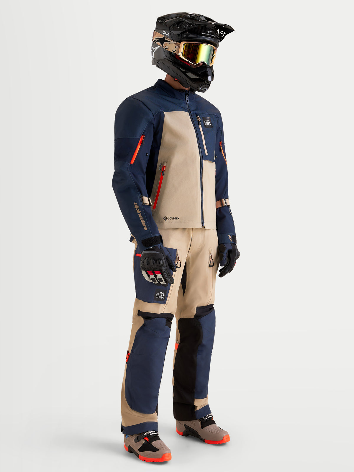 Alpinestars Arenis Gore-Tex Gear Set, casaco e calças de moto para aventura para homem em azul-marinho e alumínio, vista de perfil num modelo com equipamento e capacete a combinar, vestuário de todo-o-terreno impermeável com certificação AA