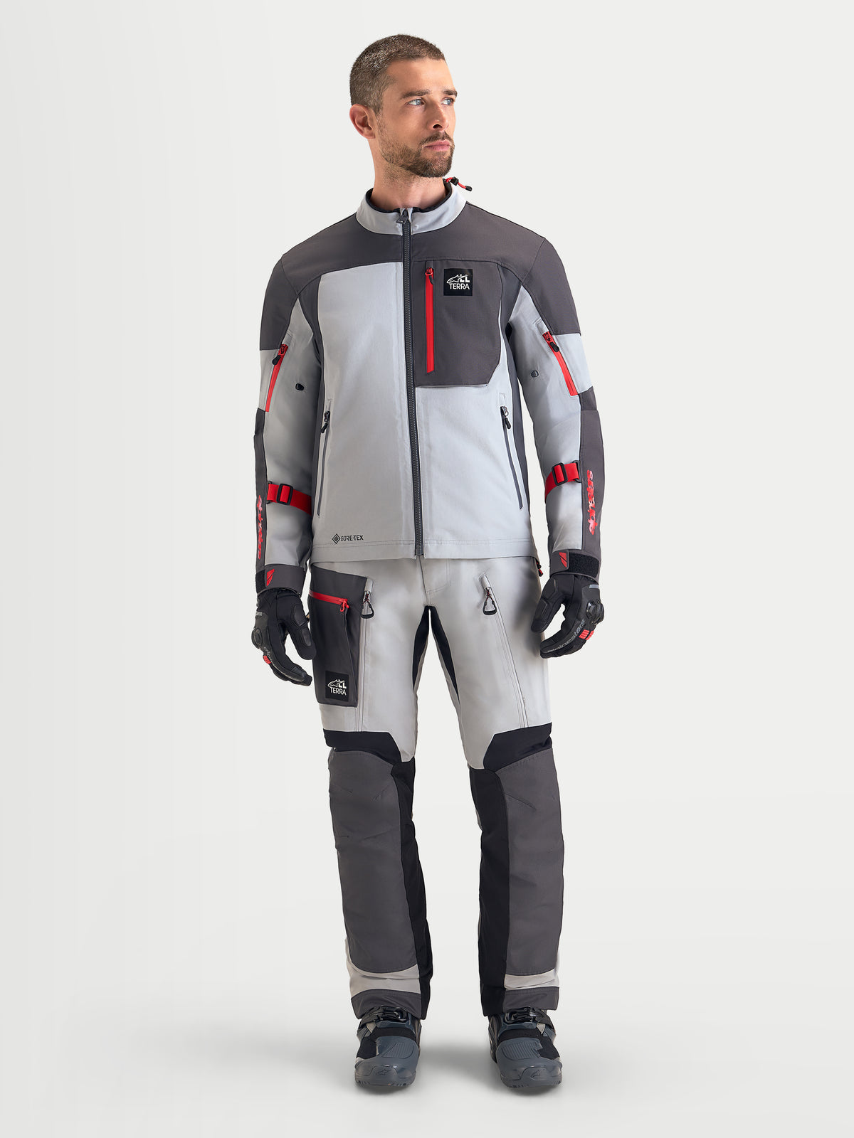 Alpinestars Arenis Gore-Tex casaco de moto para homem, cinzento-claro, cinzento-escuro e preto, vista frontal num modelo a mostrar a construção em tecido impermeável e detalhes com fecho vermelho