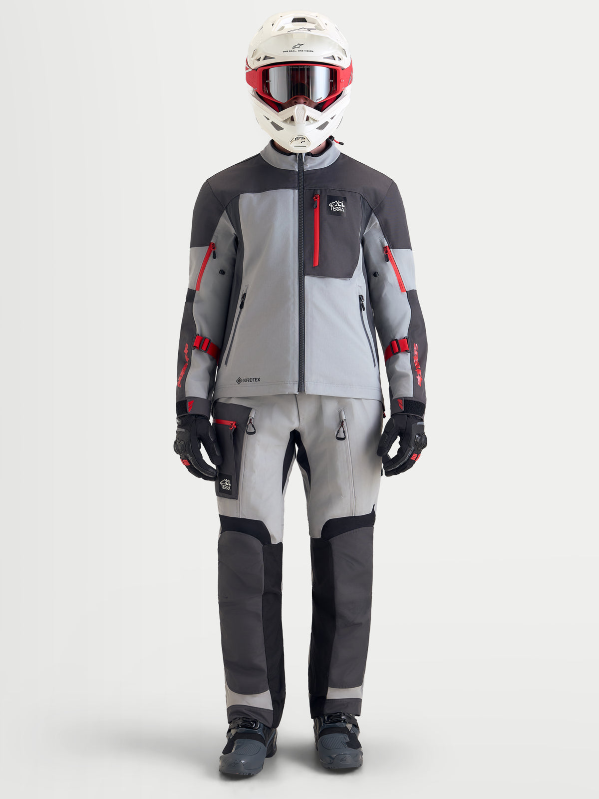 Alpinestars Arenis Gore-Tex Gear Set, casaco e calças de moto adventure para homem em cinzento, cinzento escuro e vermelho, vista frontal num modelo com equipamento e capacete a combinar, vestuário de pilotagem impermeável para todo-o-terreno