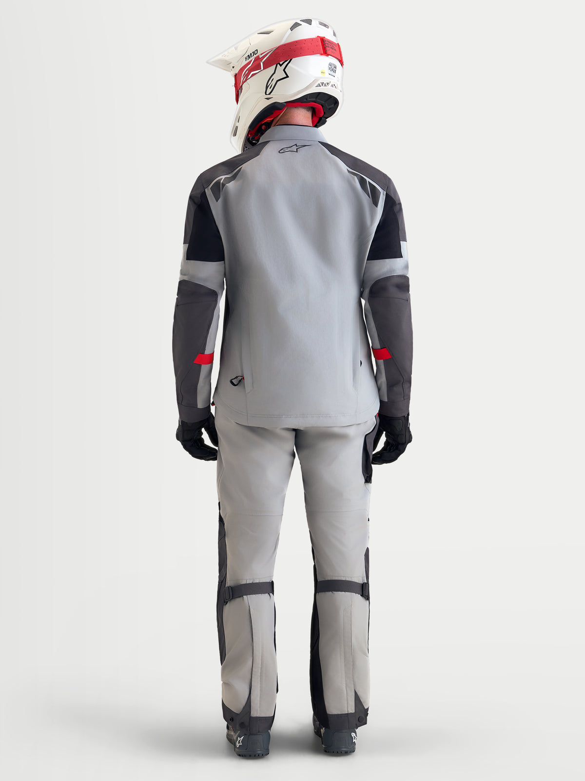 Alpinestars Arenis Gore-Tex casaco de moto adventure para homem em cinzento-médio, cinzento-escuro e preto, vista traseira a mostrar um modelo com equipamento de proteção e capacete