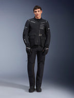 Casaco Alpinestars ST-7 2L GORE-TEX, casaco de motociclismo adventure touring, preto e cinzento escuro, usado com calças e luvas de motociclismo pretas a condizer, com vários bolsos de carga, detalhes refletores e logótipo Alpinestars Exploration Equipment no peito, design funcional para condução em estrada e fora de estrada