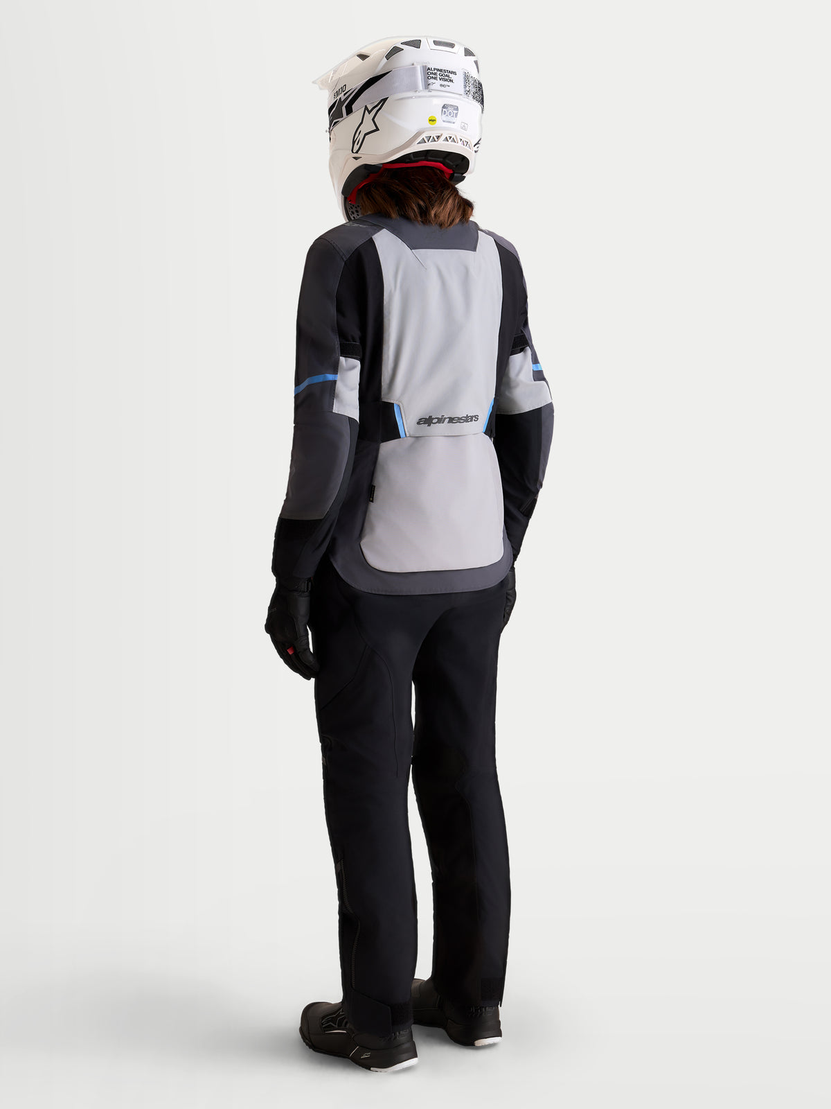 Alpinestars Stella ST-7 V2 2L Gore-Tex® Jacket, women's adventure touring motorcycle jacket in mid gray, deep gray, and black, rear profile view on a model wearing matching gear and helmet, waterproof textile construction.
