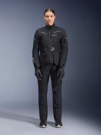 Motociclista feminina a usar Casaco e Calças Alpinestars Stella ST-7 2L GORE-TEX, fato de touring preto para motociclismo, equipamento técnico impermeável e respirável, com luvas e botas pretas a condizer, equipamento de proteção integral com elementos refletores, design técnico moderno para condução de aventura