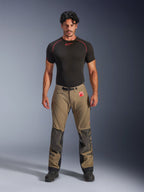 Modelo masculino a vestir Calças Alpinestars Nazca 3L GORE-TEX PRO em castanho nogueira e preto, equipamento técnico de aventura com reforços de joelho em Superfabric e fivela magnética na cintura, combinado com uma camisola de base preta Alpinestars, vista frontal de estúdio.