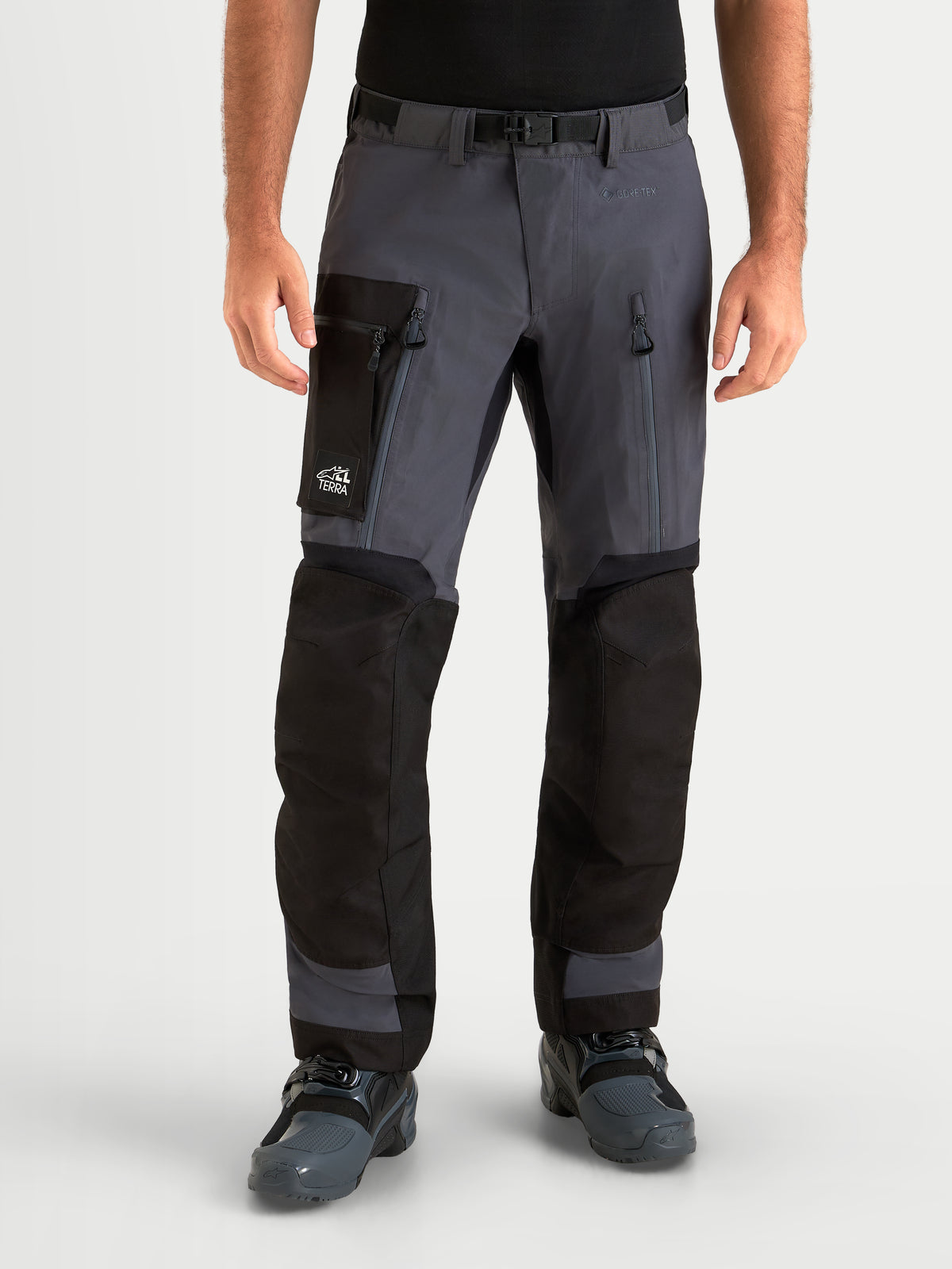 Alpinestars Arenis Gore-Tex calças, calças de moto para aventura para homem, preto e cinzento escuro, vista frontal num modelo a mostrar vestuário impermeável com bolsos cargo e entradas de ar nas coxas