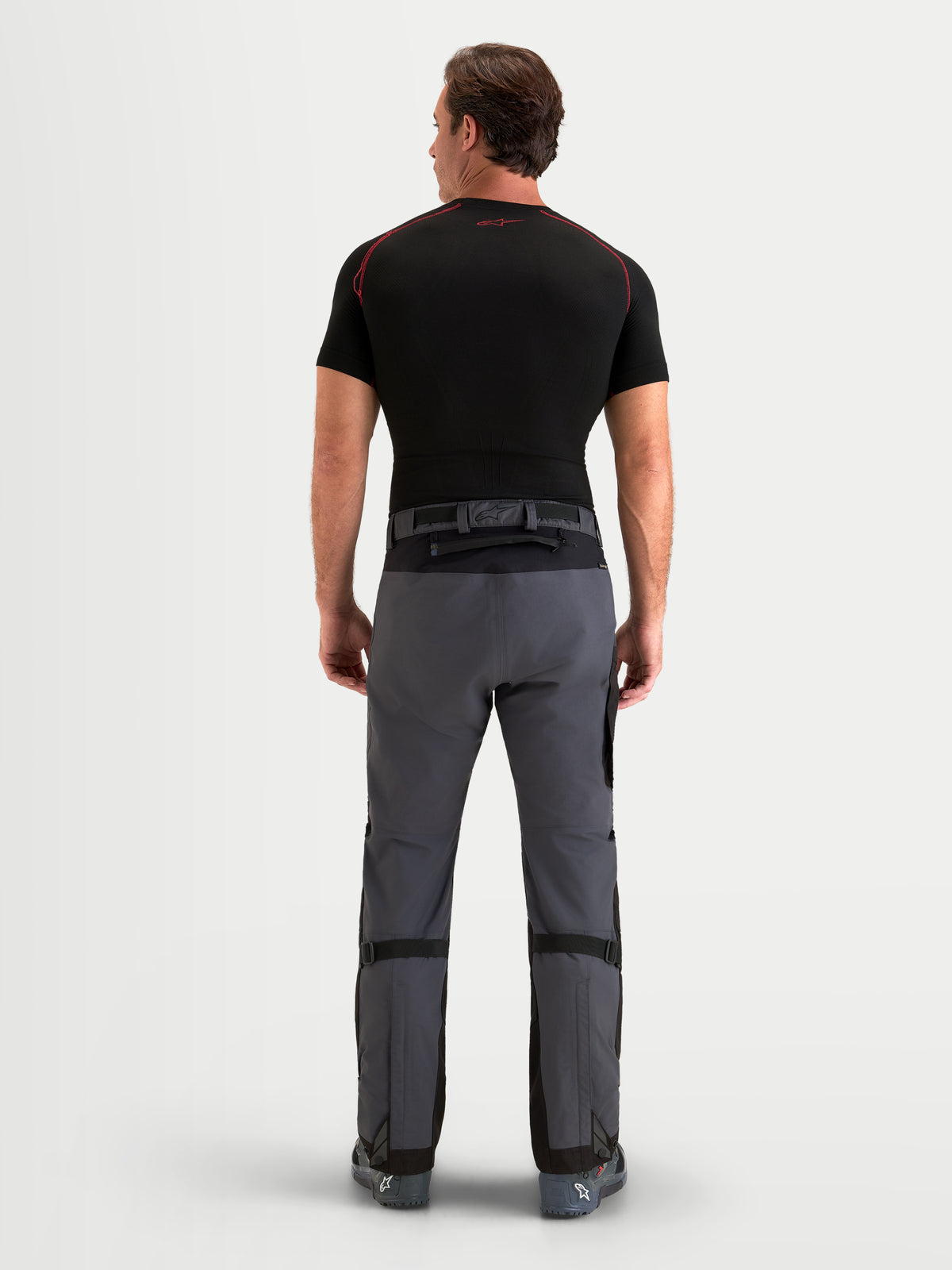 Alpinestars Arenis Gore-Tex calças, calças de moto para aventura para homem, pretas e cinzentas, vista traseira num modelo a mostrar a construção em tecido impermeável e o fecho da cintura