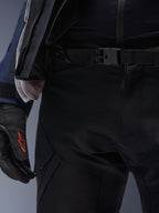 Calças Alpinestars ST-7 2L GORE-TEX, pretas, grande plano da cintura com fecho de fivela magnética e construção em tecido técnico durável, usadas com casaco de turismo de aventura a condizer e luvas pretas com logótipo vermelho.