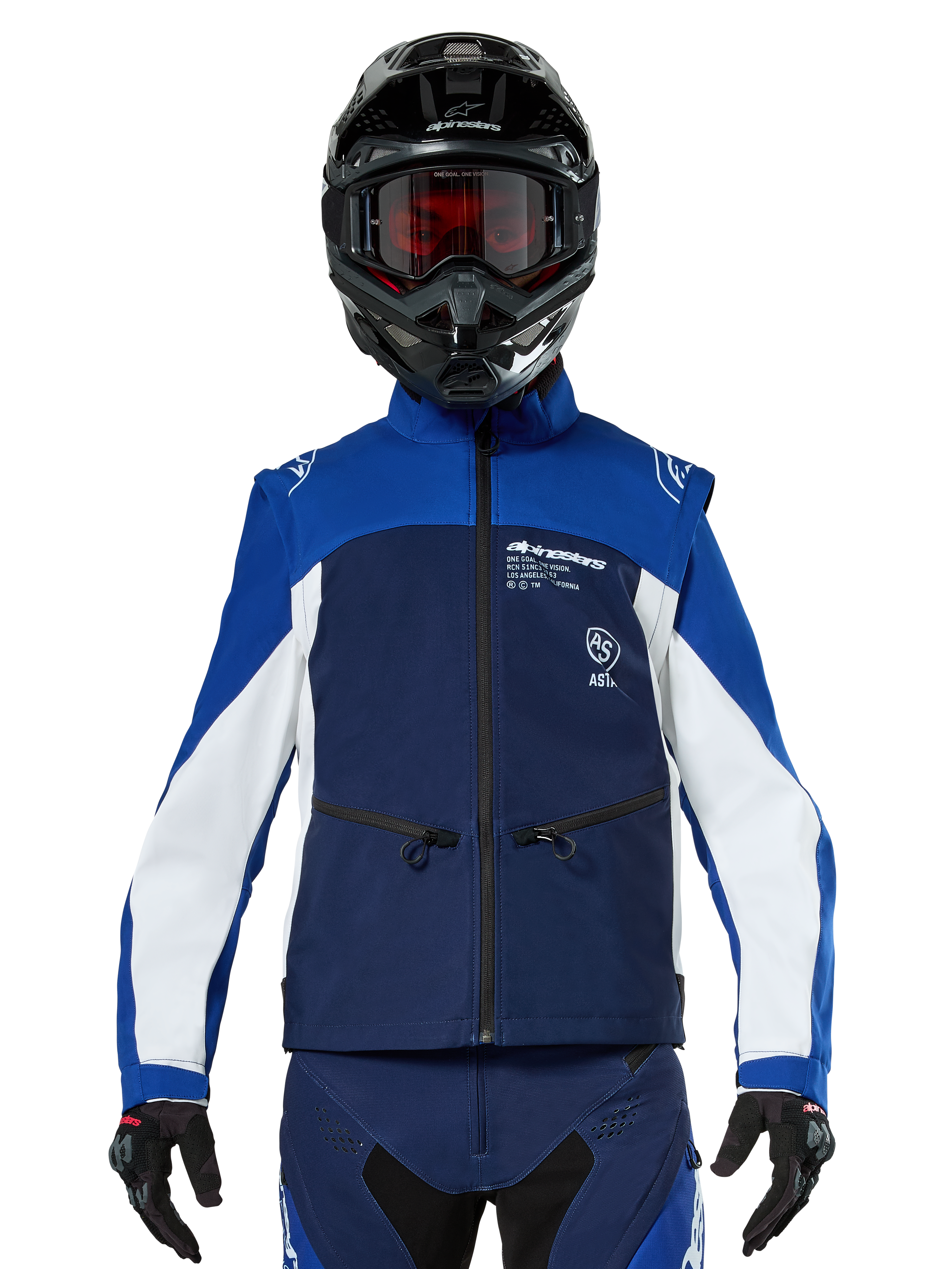 Motocross rider wearing the Alpinestars Lite-Dura Softshell Jacket in Navy Bright Blue White, front view, paired with a black helmet and red-tinted goggles, featuring a technical windproof design with zippered pockets and white accents for off-road enduro riding