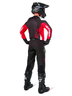 Motocross rider from behind wearing Alpinestars Pro-Dura Pants in Black Magnet White, paired with a red and black jersey and black boots, coordinated off-road gear set for enduro riding