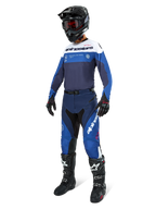 Piloto de motocross equipado com calças Alpinestars Pro-Dura em azul marinho, azul brilhante e branco, camisola de manga comprida a condizer, capacete preto com óculos vermelhos, luvas pretas e botas pretas e brancas, conjunto coordenado para corridas de enduro e off-road.