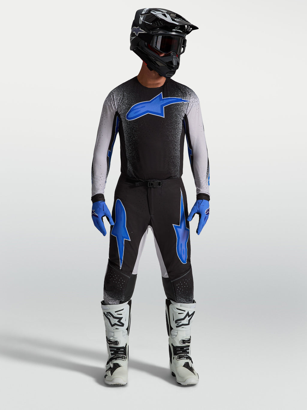 Alpinestars calças Supertech Hiten AFD, calças de motocross pretas e azuis, com camisola a condizer e botas de moto brancas.