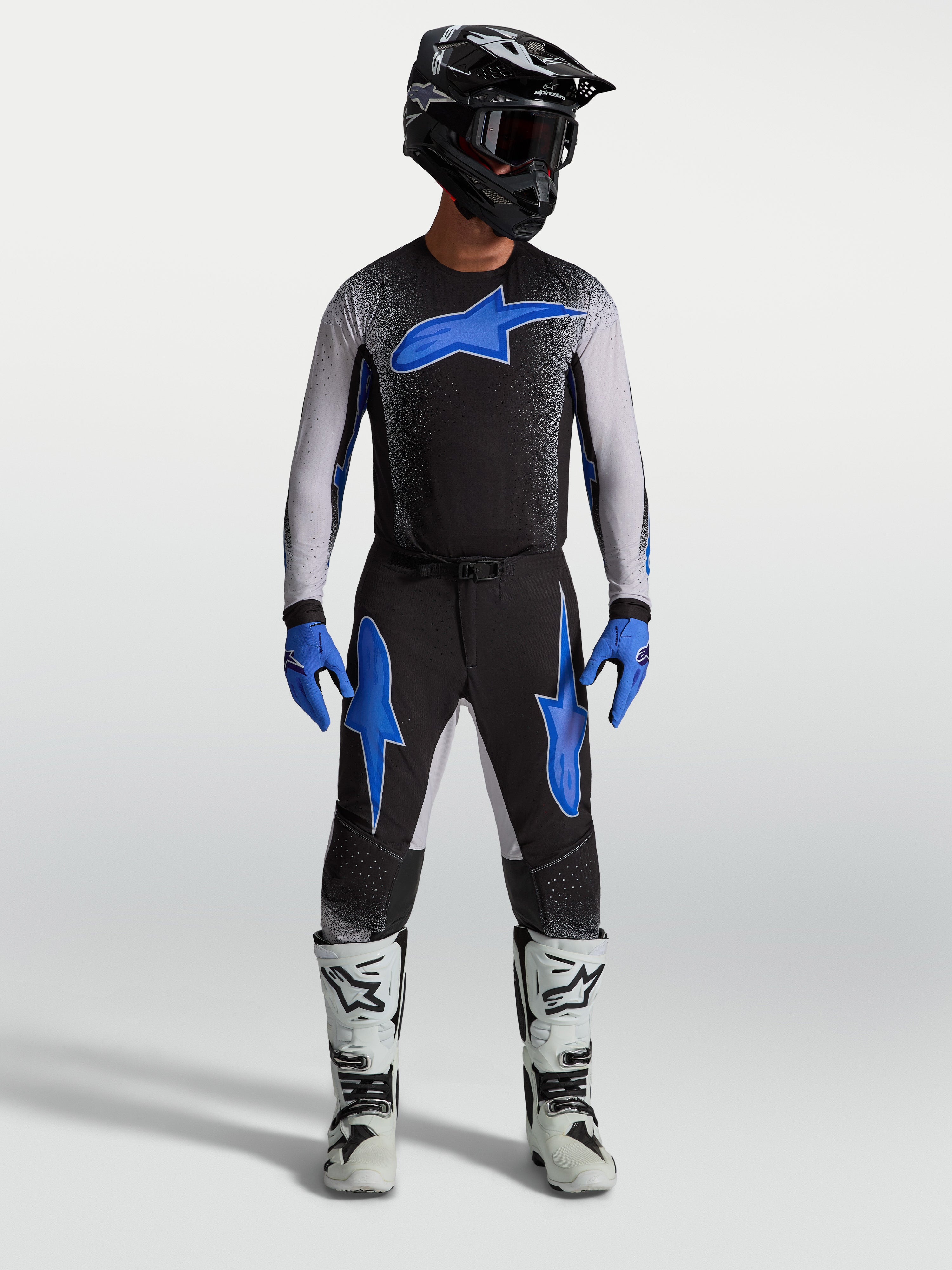 Alpinestars calças Supertech Hiten AFD, calças de motocross pretas e azuis, com camisola a condizer e botas de moto brancas.