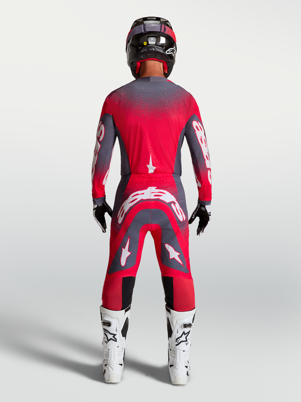 Alpinestars Supertech Hiten AFD Gear Set e calças, equipamento de corrida de motocross para homem, vermelho fluorescente e cinzento, vista traseira no modelo com botas e capacete.