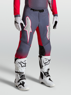 Alpinestars Supertech Hiten AFD, cal'cas de motocross cinzentas e vermelho fluo, com grafismos de estrela brancos e fivela magn)tica, usadas com botas.