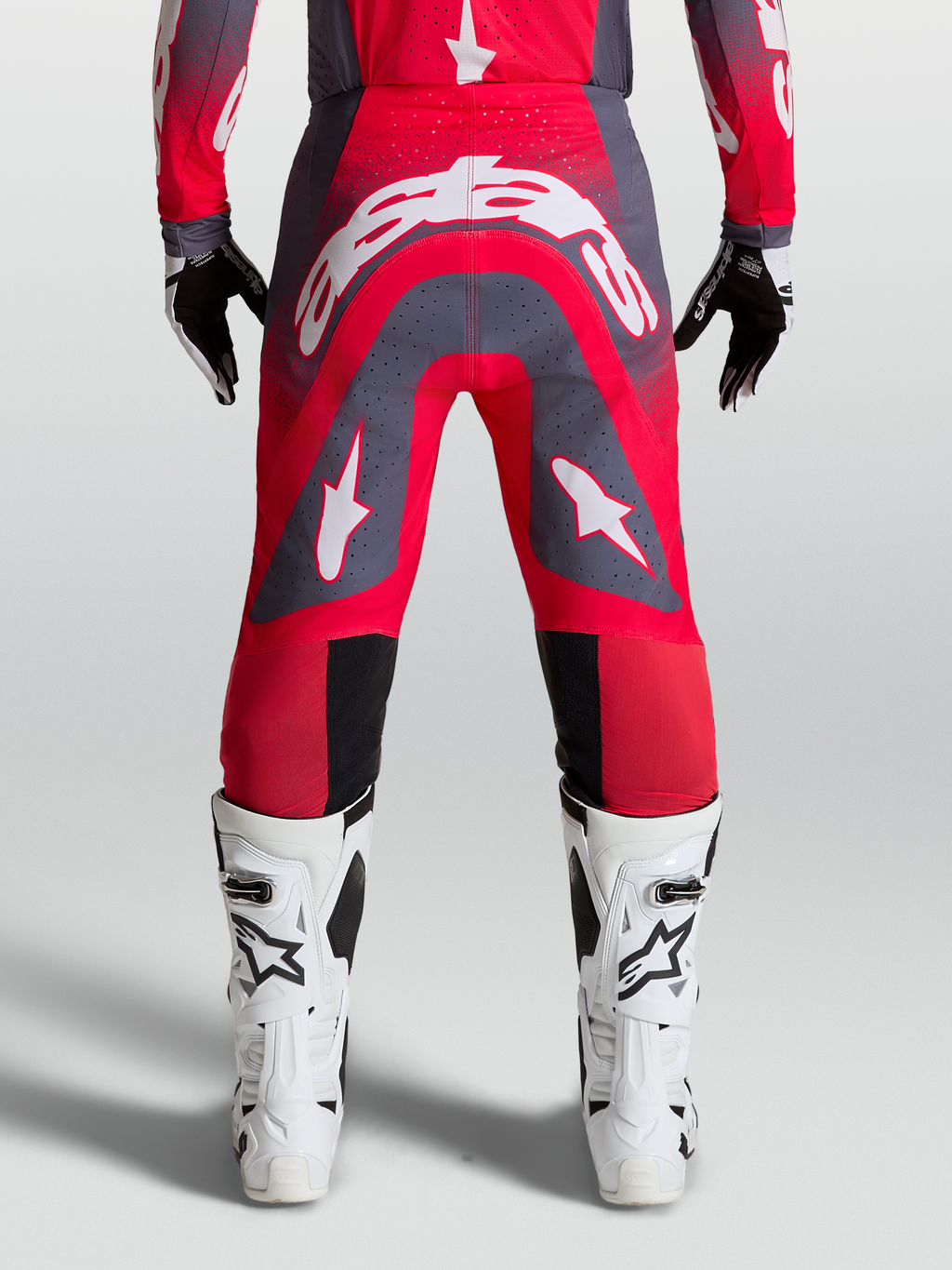 Alpinestars Supertech Hiten AFD, calças de motocross profissionais, vermelho fluorescente e cinzento, vista traseira em modelo com logótipo branco, equipamento de corrida todo-o-terreno