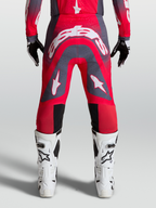 Alpinestars Supertech Hiten AFD, calças de motocross profissionais, vermelho fluorescente e cinzento, vista traseira em modelo com logótipo branco, equipamento de corrida todo-o-terreno
