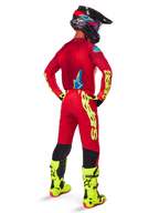 Alpinestars 2025 Supertech Maker Pants, Motocross Pants, Bright Red and Yellow Fluo, seen from behind on a rider wearing a matching red jersey, fluorescent yellow boots, and black helmet, featuring large yellow Alpinestars branding on the leg.
