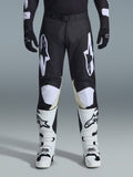 Alpinestars 2026 Racer Air Riway Pants, calças de motocross, pretas e brancas, com logótipos Alpinestars brancos em destaque nas coxas e nos painéis dos joelhos, combinadas com botas de motocross brancas e pretas e luvas pretas, design de ajuste desportivo de corrida para condução off-road