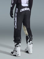 Calças Alpinestars 2026 Racer Air Riway, calças de motocross, pretas e brancas, vista traseira com branding Astars grande em branco no assento e nas pernas, painéis internos dos joelhos em couro bege, usadas com botas Tech 7 brancas e pretas, vestuário de corrida off-road premium